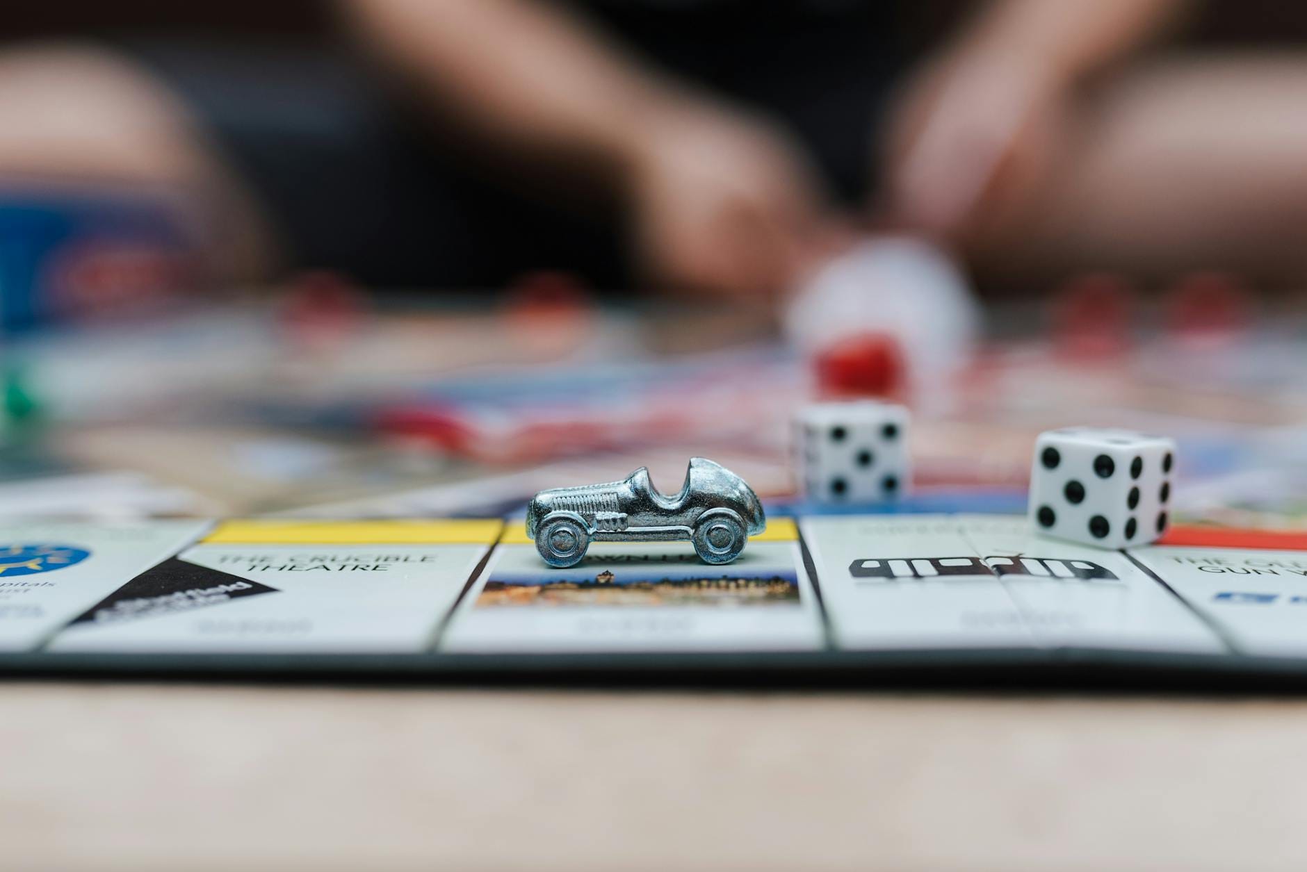 Dłonie mężczyzny przesuwające pionki na planszy gry Monopoly