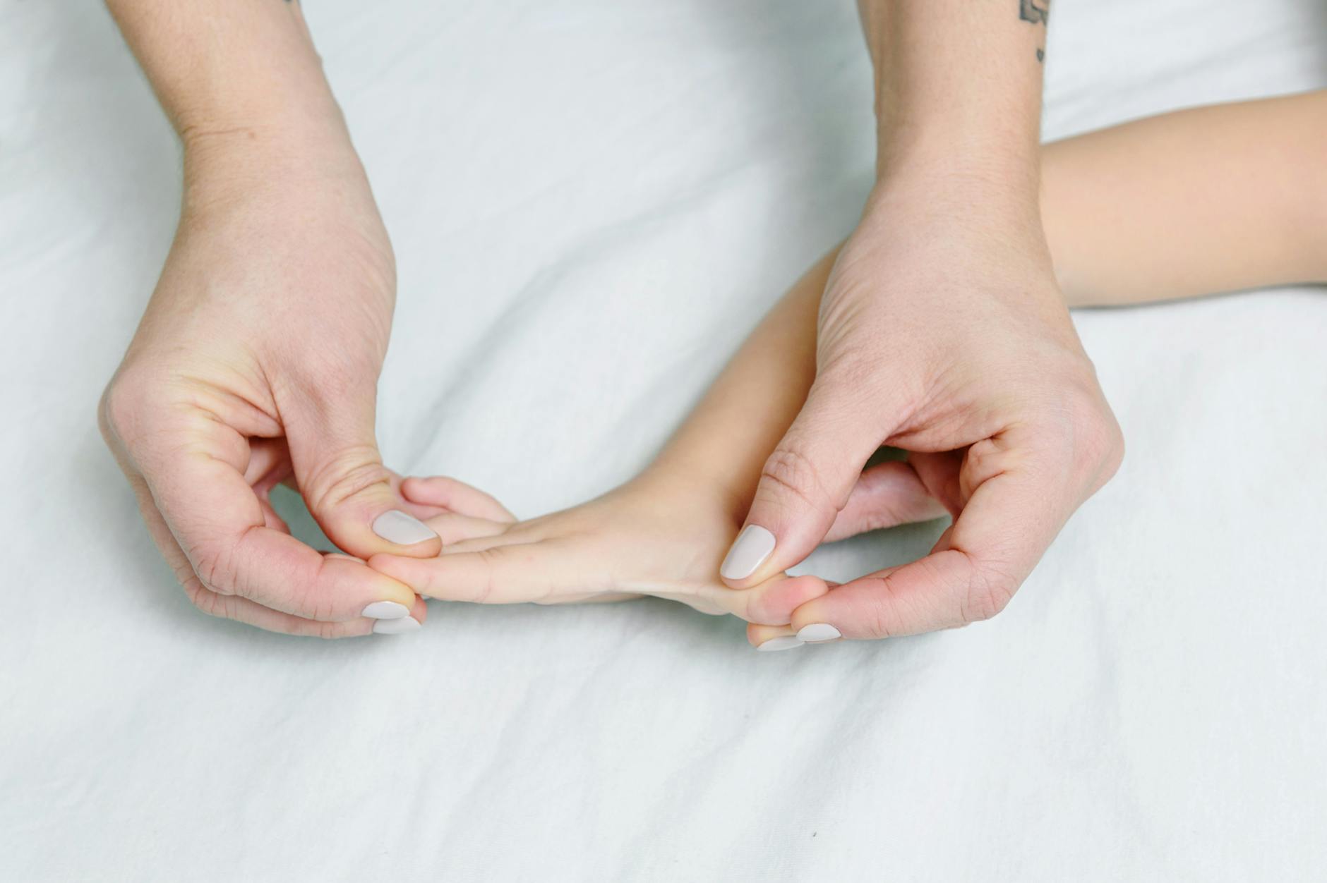 Znaczenie rehabilitacji neurologopedycznej dla niemowląt z zaburzeniami rozwoju psychoruchowego Dłonie osoby dorosłej delikatnie masują dłoń niemowlęcia