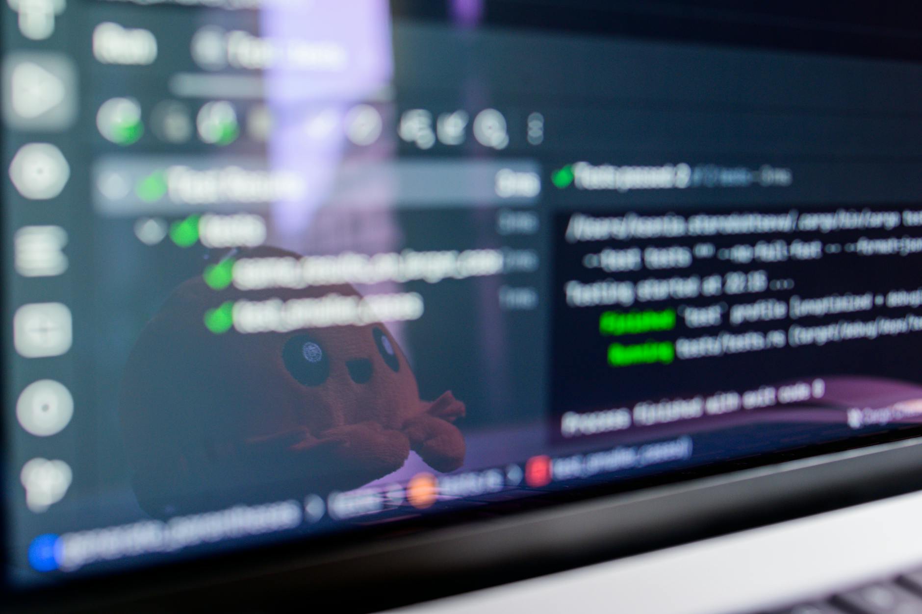 Ekran laptopa z kodem gry i odbijającą się maskotką