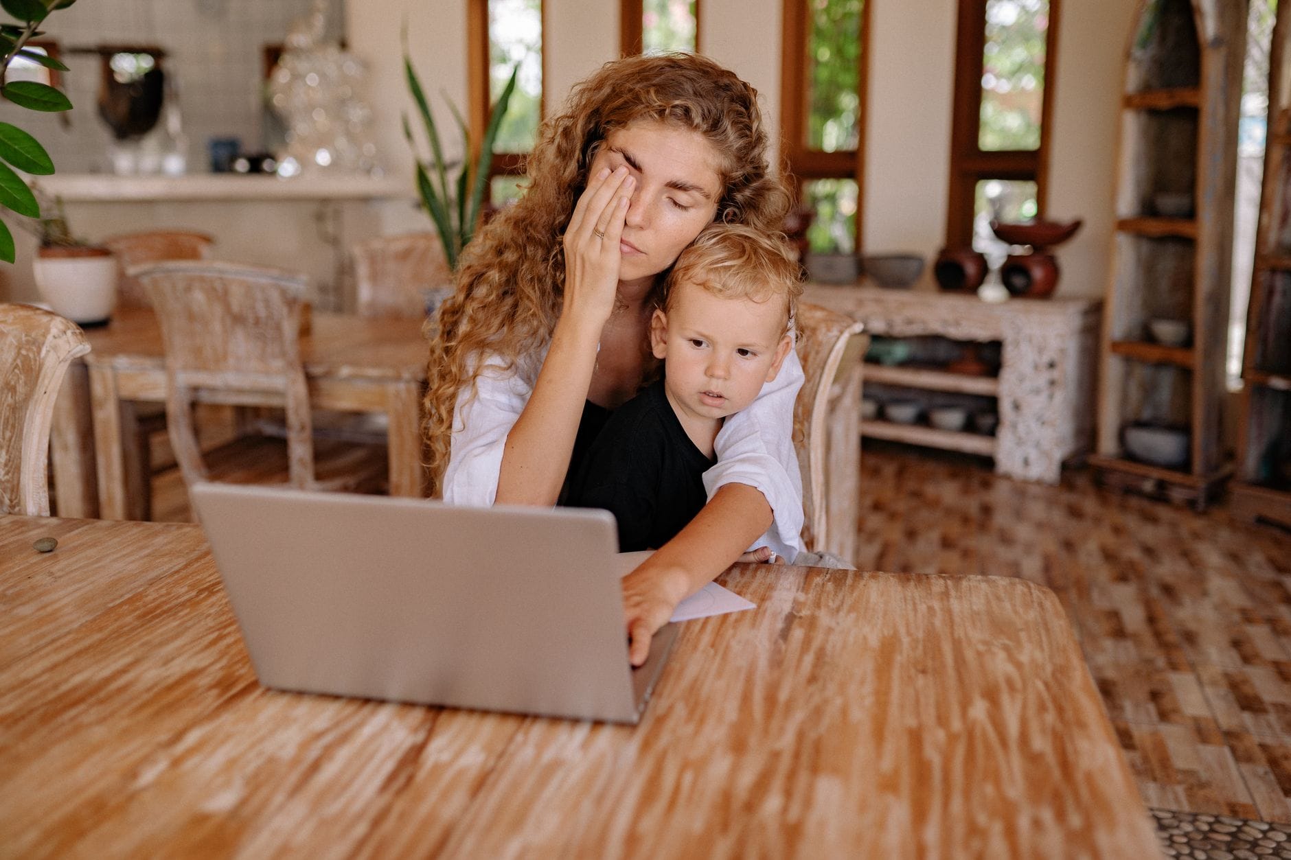 Mama pracująca przy laptopie w domu z dzieckiem na kolanach